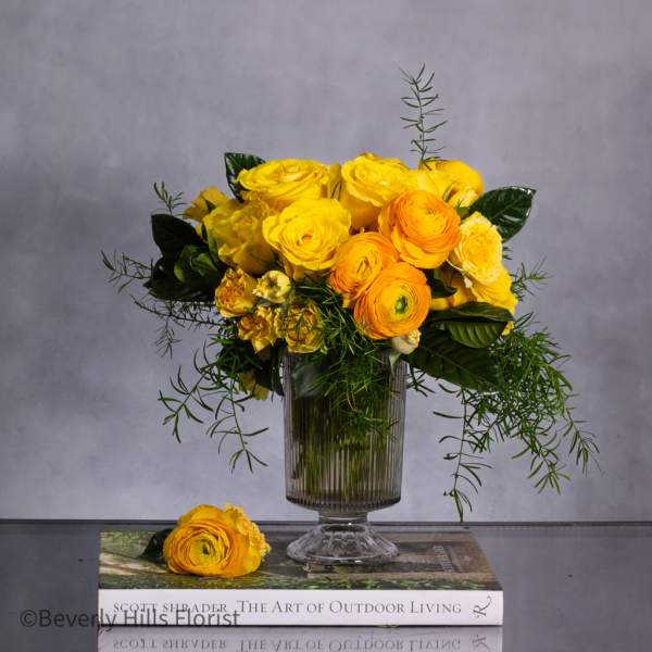 Yellow and orange flower arrangement in a clear glass vase