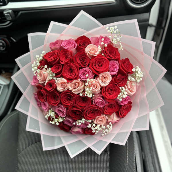 Bouquet of red and pink roses wrapped in translucent paper