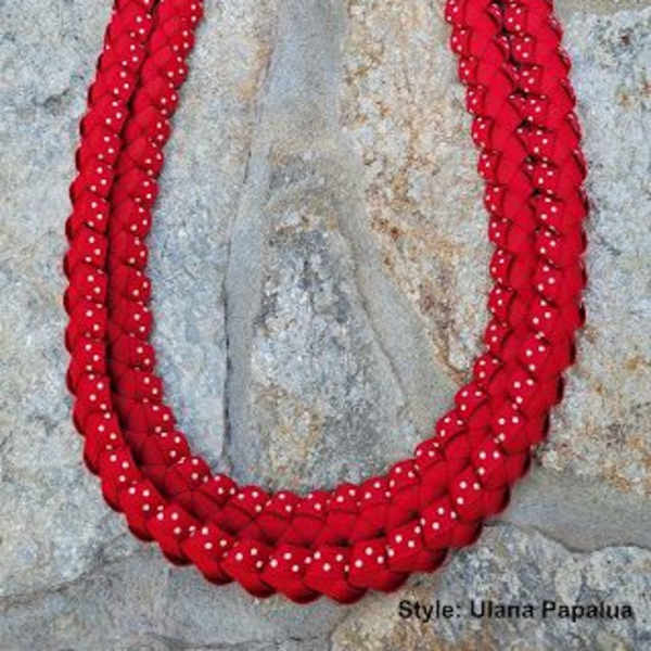 Red braided lei with white dots on a stone background