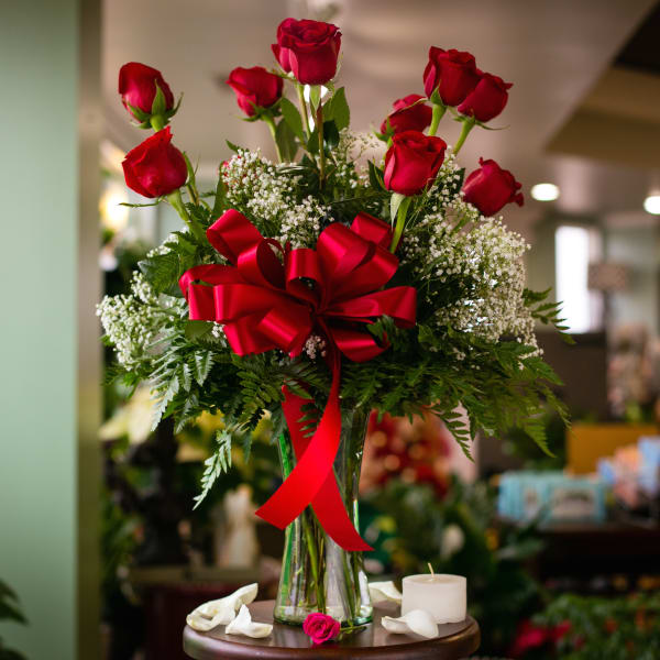 Red roses in a glass vase with a red ribbon bow