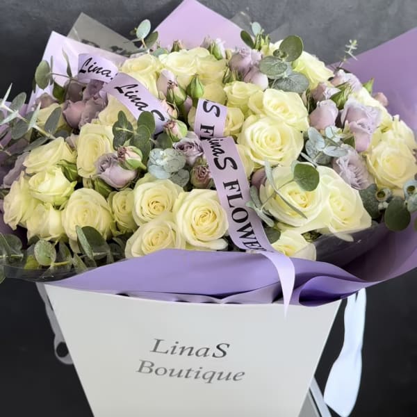 Bouquet of cream roses and pale lavender flowers in a gift box