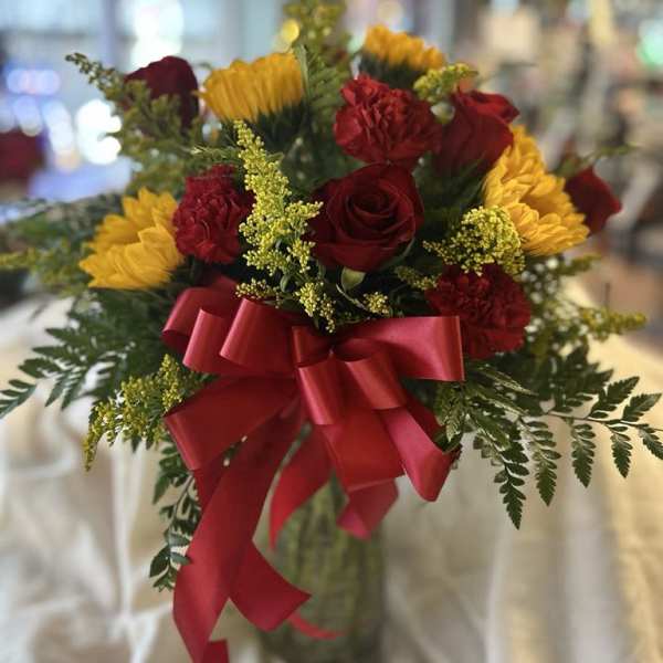 Bouquet of red roses, red carnations, and yellow flowers with a red ribbon