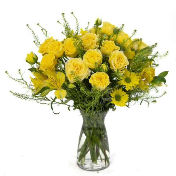 Bright yellow roses and daisies arranged in a clear glass vase
