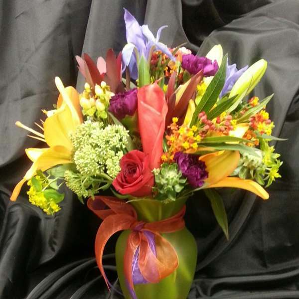 Colorful mixed bouquet in a green vase with a ribbon bow