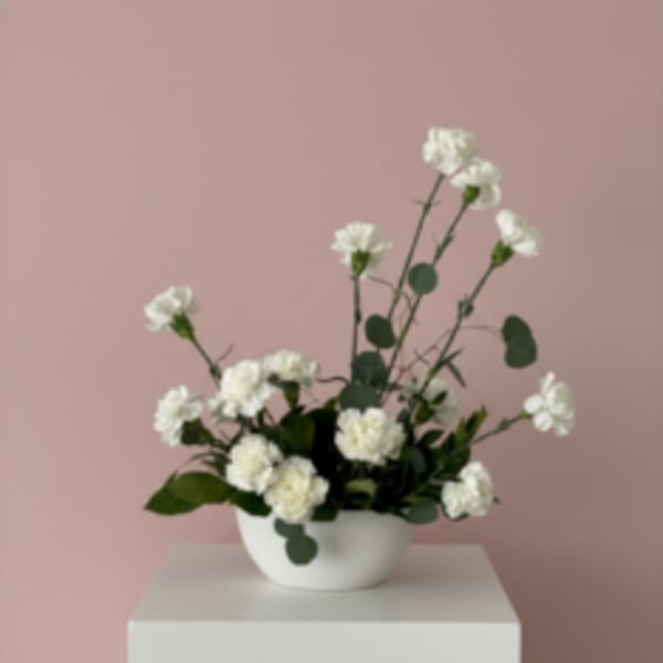 White carnations in a white bowl vase on a pedestal