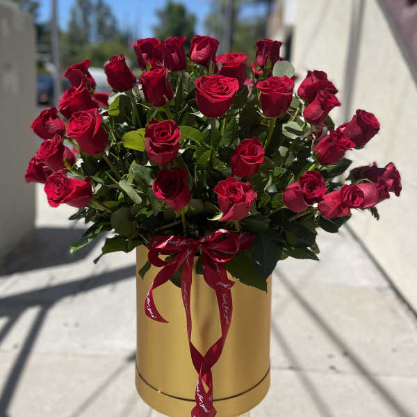 Bouquet of red roses in a gold hatbox with a red ribbon
