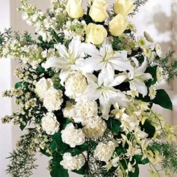 White lilies and pale yellow roses in a standing floral spray
