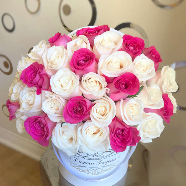 Round box of white and hot pink roses arranged tightly in a white hatbox container