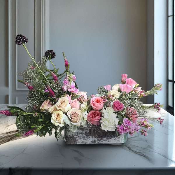 Low floral arrangement with pink and cream roses in a rectangular vase