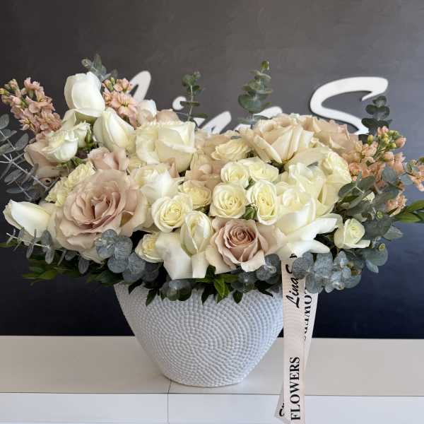 Cream and blush rose arrangement in a white textured vase