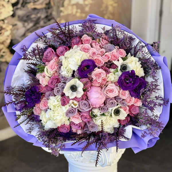 Bouquet of pink, lavender, white, and purple roses with white anemones