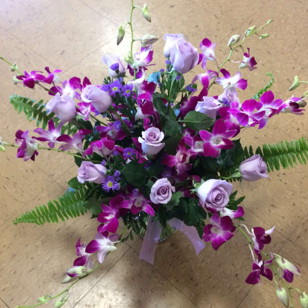 Bouquet of purple orchids and lavender roses in a glass vase