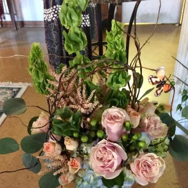 Pink roses and blue hydrangea in a low container with tall green accents