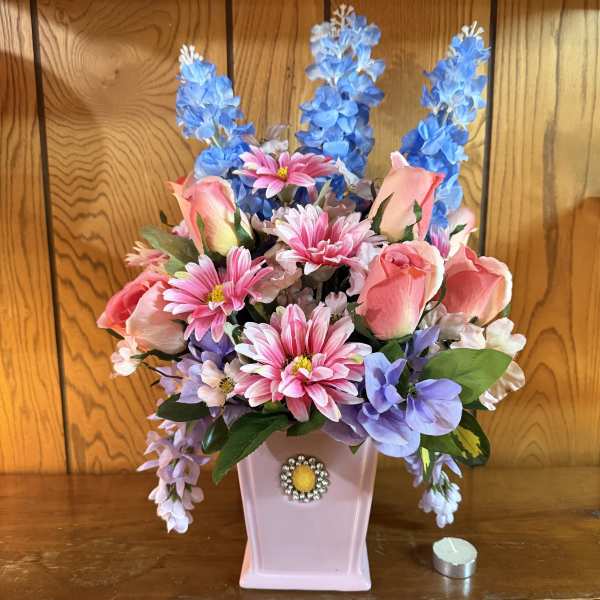 Pink and blue artificial flower arrangement in a pink vase