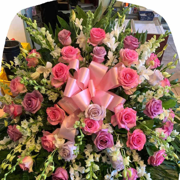 Large bouquet of pink and lavender roses with white orchids and a pink ribbon