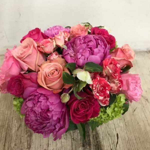 Bouquet of pink and purple roses with peonies on a wooden surface