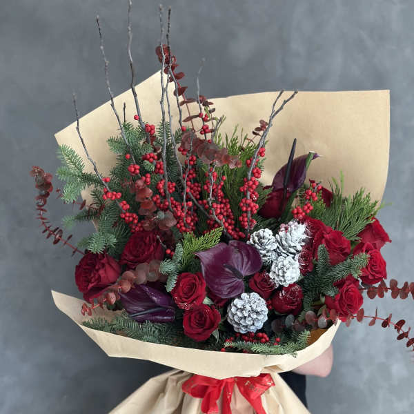 Bouquet of red roses with burgundy calla lilies and berries in kraft paper