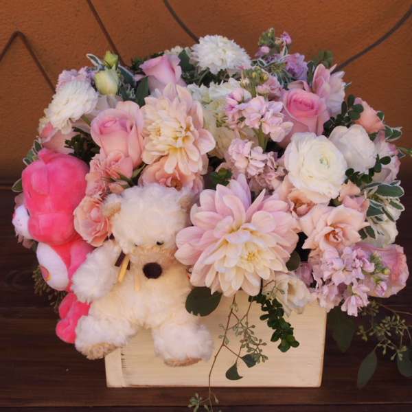 Pink and white flower arrangement in a wooden box with a teddy bear