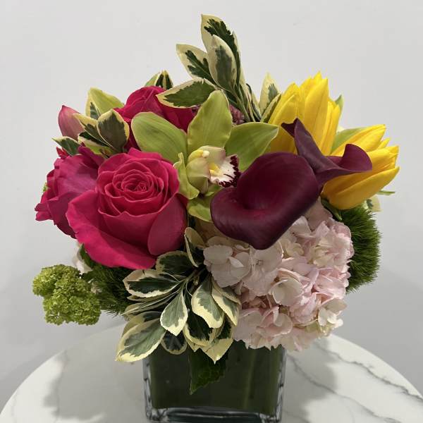 Bright mixed bouquet in a square glass vase