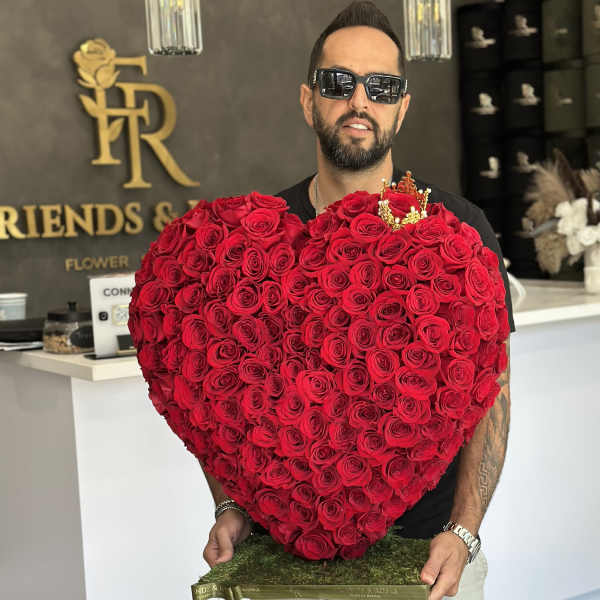 Man holding a large heart-shaped arrangement of red roses