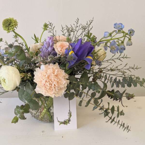 Mixed bouquet in a glass vase with blue, peach, and white flowers