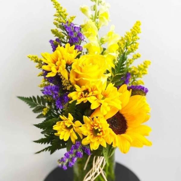 Yellow and purple mixed flower arrangement in a glass vase