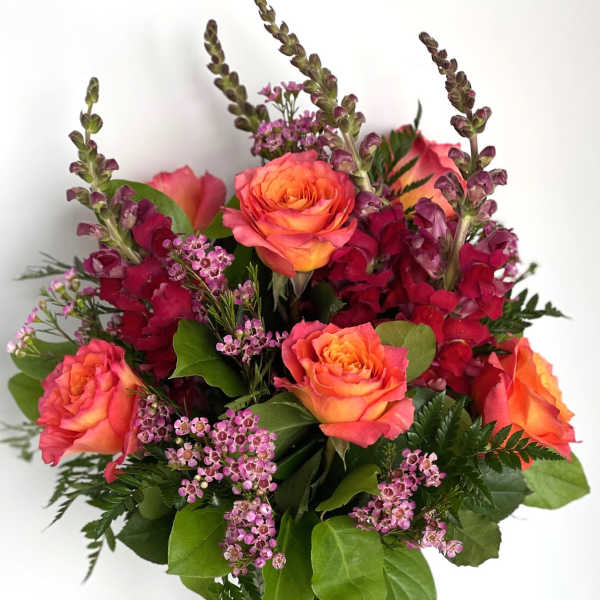 Bouquet of orange roses and pink flowers in a clear glass vase