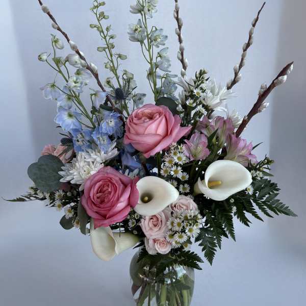 Pink roses and white calla lilies in a glass vase with blue and white flowers