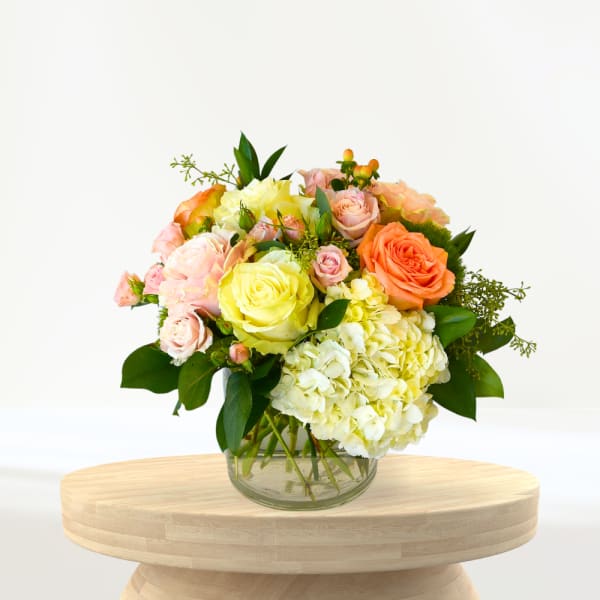 Bouquet of pastel roses and hydrangeas in a clear glass vase