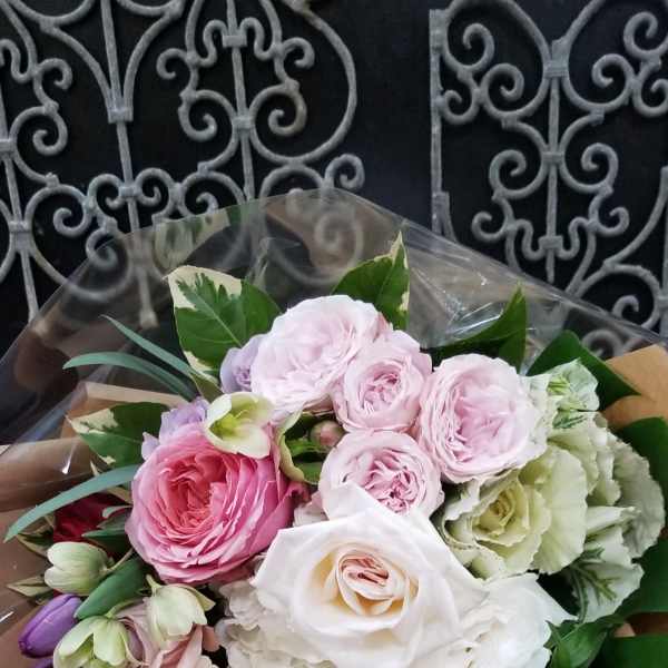 Bouquet of pink, white, and purple roses wrapped in brown paper