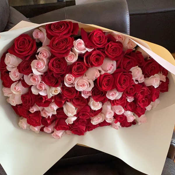 Large bouquet of red and pale pink roses wrapped in white paper