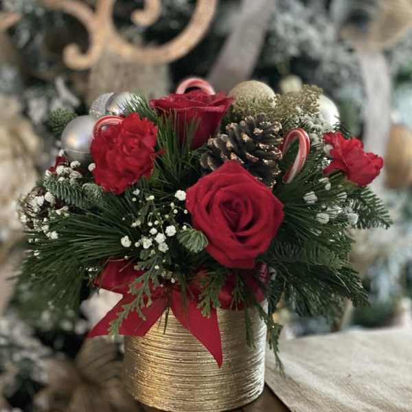 Red roses and carnations in a gold vase with pinecones and ornaments
