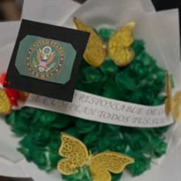 Green floral wreath with yellow butterfly accents and a memorial ribbon