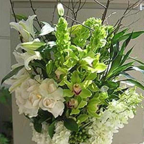 Tall white and green floral arrangement in a clear glass vase