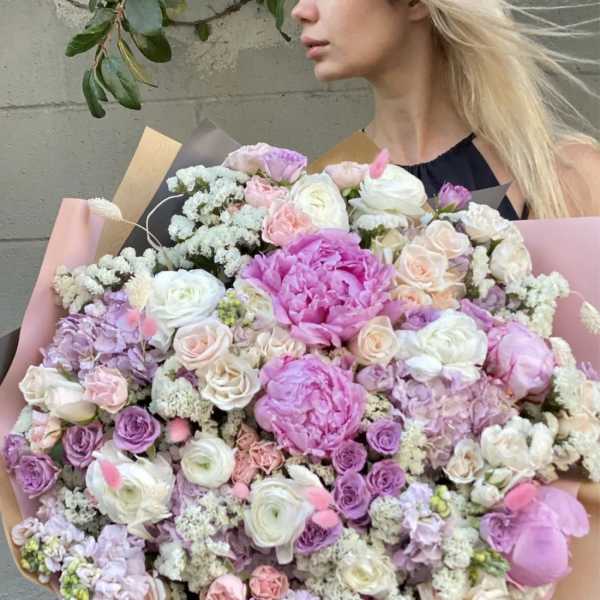 Large pastel bouquet of pink, lavender, and white flowers wrapped in paper
