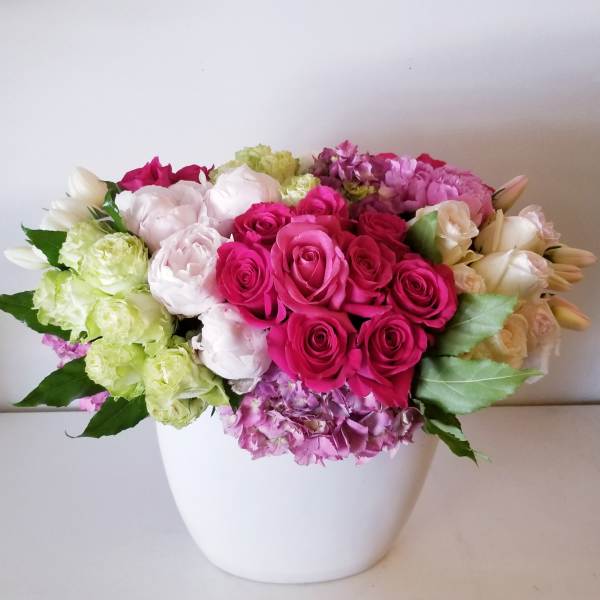 Pink and white roses arranged in a white vase