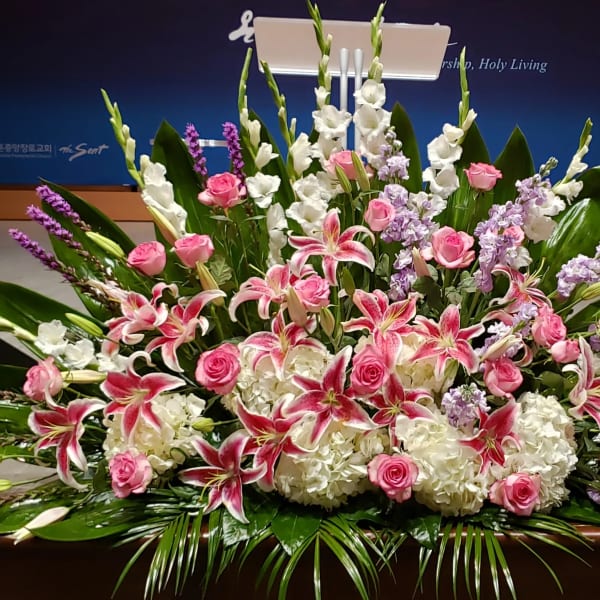 Large pink and white lily and rose arrangement with hydrangeas and lavender flowers in a low spray design