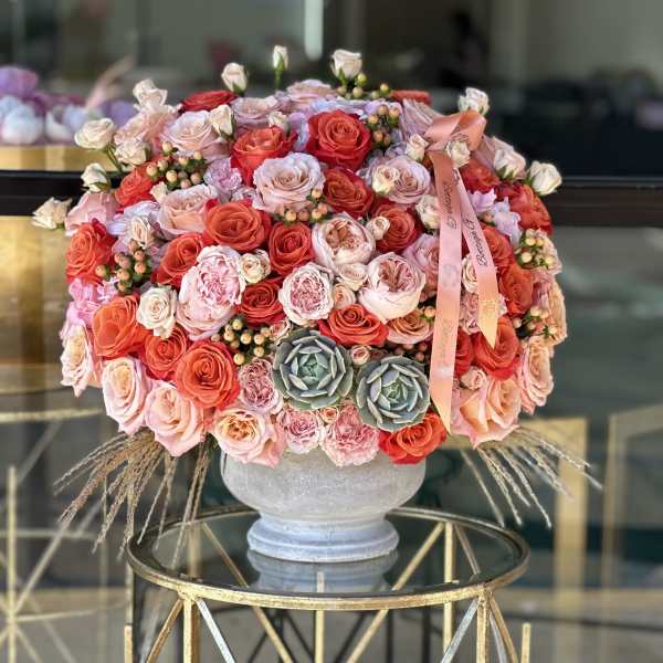 Round bouquet of pink and coral roses in a gray vase