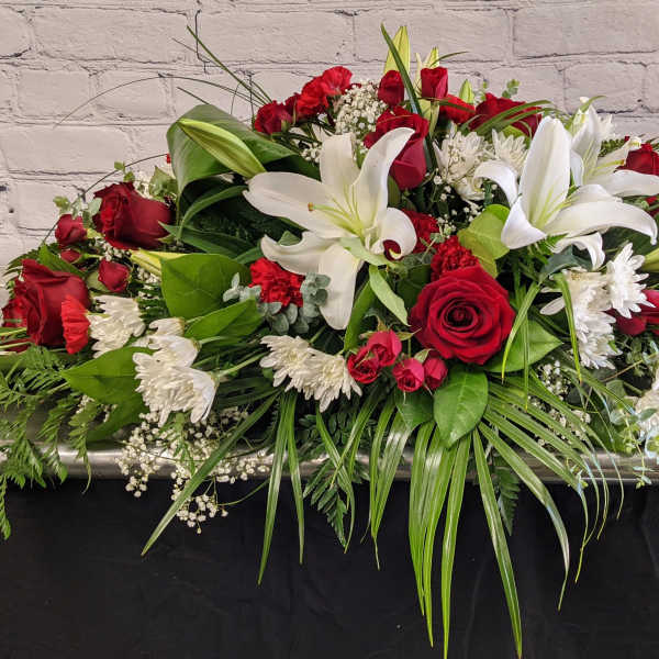 Casket spray with red roses, white lilies, and white chrysanthemums