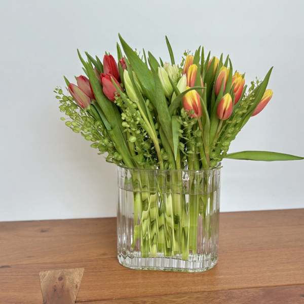 Bouquet of red, yellow, and white tulips in a clear glass vase