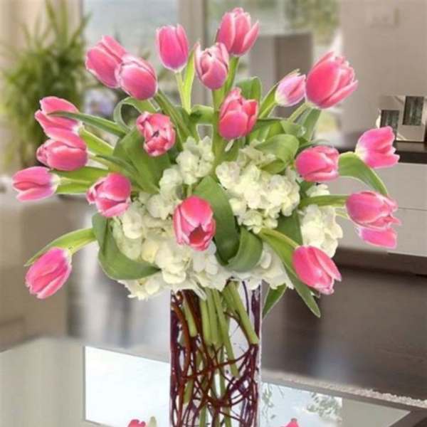 Pink tulips arranged with white hydrangeas in a clear glass vase