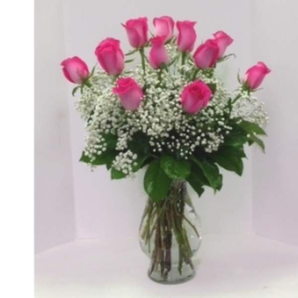 Pink roses arranged in a clear glass vase with white baby's breath