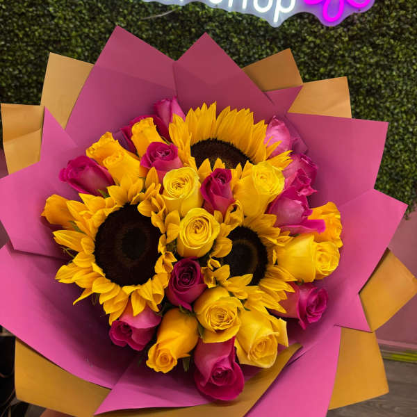 Bouquet of yellow sunflowers and pink and yellow roses wrapped in magenta paper