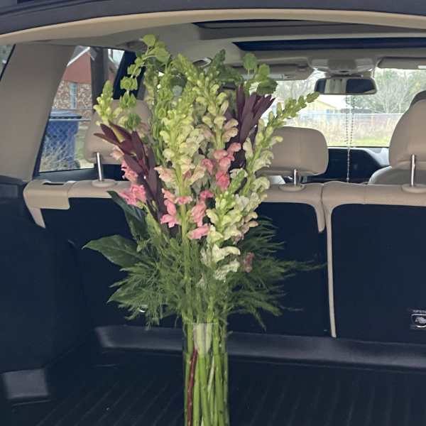 Tall mixed bouquet of pink and green flowers in a glass vase