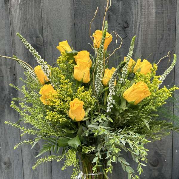 Yellow roses in a clear glass vase with airy greenery
