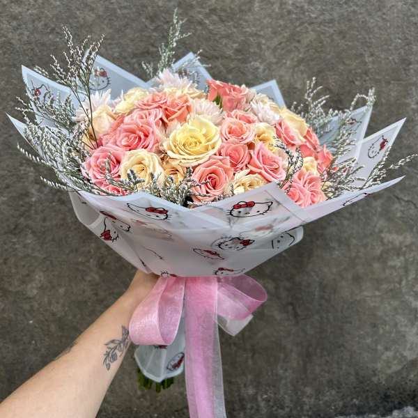 Bouquet of pink and yellow roses wrapped in Hello Kitty paper with a pink ribbon