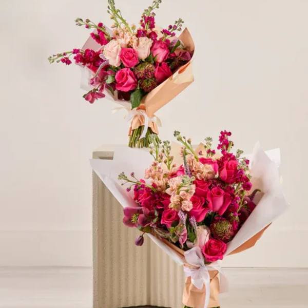 Two pink and peach flower bouquets wrapped in paper
