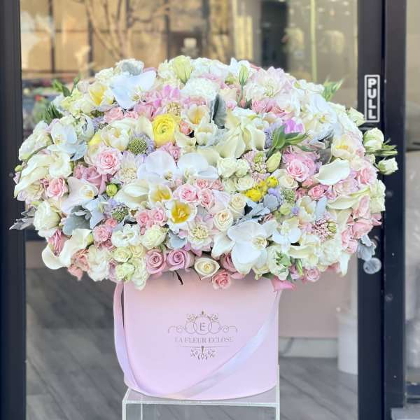 Large pastel flower arrangement in a pink hat box