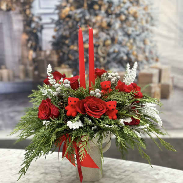 Red roses and holiday greenery in a vase with two red candles