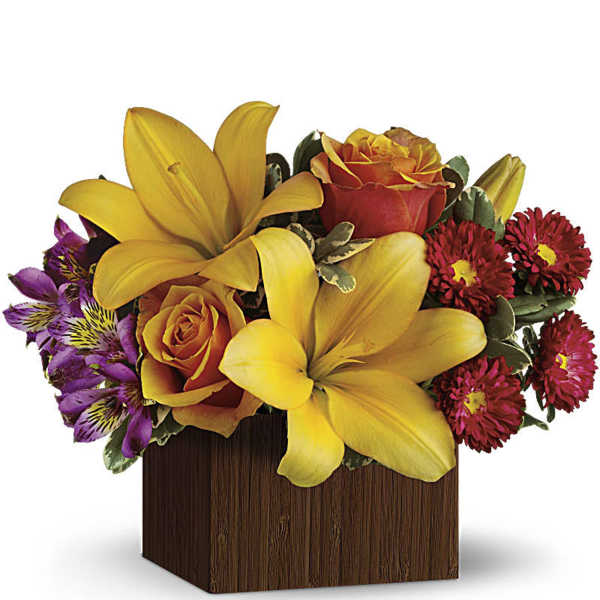 Yellow lilies and orange roses in a wooden cube vase with purple flowers